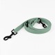 Eine mintgrüne Hundeleine mit schwarzen Metallclips, ordentlich auf einem weißen Hintergrund aufgerollt.