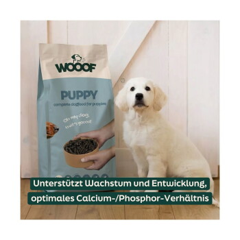 Cremefarbener Welpe neben einer WOOOF-'PUPPY'-Hundefuttertüte, sichtbarer Text 'PUPPY' und deutsches Banner 'Unterstützt Wachstum und Entwicklung'