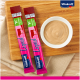 Zwei Vitakraft Liquid Snack Röhren in Pink und Grün neben einer weißen Schüssel mit beigem Snack auf einem Holzschneidebrett.