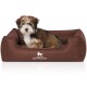 Ein kleiner, flauschiger Hund sitzt bequem in einem braunen Hundebett mit dem Logo "KNUFFELWUFF" auf der Vorderseite.
