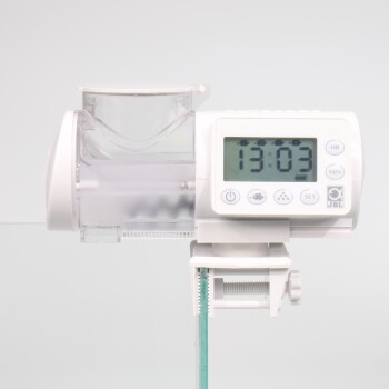 Digitaler automatischer Fischfütterer mit einem klaren Futterbehälter und einer digitalen Uhr, die 13:03 anzeigt, montiert auf einem Glastank.