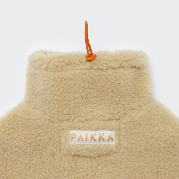 Beiger Sherpa-Haustiermantel-Rückenkragen mit orangefarbener Kordel und Stopper; Etikett mit der Aufschrift 'PAIKKA'.