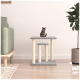 Ein stilvoller Katzenbaum mit zwei Plattformen, mit einer getigerten Katze, die auf der obersten Ebene sitzt, neben einem grünen Sofa und einer Topfpflanze.