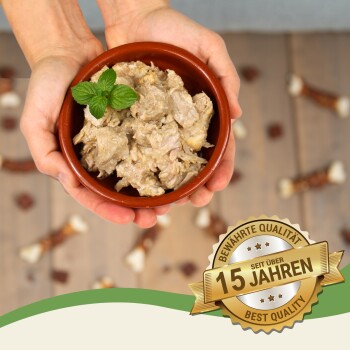 Eine Person hält eine Schüssel mit Tierfutter, auf der ein Minzblatt liegt, umgeben von Hundeleckerlis, mit einem Abzeichen, das "Beste Qualität" und "15 Jahre" angibt.