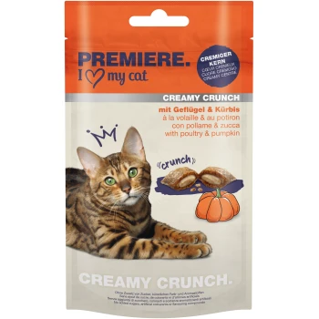 A Bengal cat lies beside a package of "Premiere I Love My Cat Creamy Crunch" treats, featuring poultry and pumpkin, with a crunchy texture.