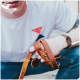 Ein junger Mann in einem weißen T-Shirt hält ein Set brauner Leder-Hundeleinen und einen Schlüsselanhänger mit einer Hundesilhouette, während er eine Uhr trägt.