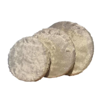 Drei runde, plüschige Haustierkissen in einem sanften Beigeton, leicht schief gestapelt, die ihre flauschige Textur zeigen.