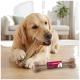 Golden Retriever kaut an einem Knochen auf dem Wohnzimmersboden; verpackter Knochen daneben mit Aufschrift "FIT+FUN KAUKNOCHEN".