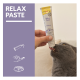 Graue Katze leckt an einer von Hand gehaltenen GimCat 'Relax Paste'-Tube; linke Tafel zeigt 'RELAX PASTE' auf lila Hintergrund.