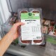 Hand hält verpackte Tiefkühlschale mit Hundefutter 'Komplett‑Mix Rind' (BARFER'S Komplett), 400 g, im Gefrierschrank.