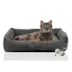 Ein gemütliches graues Katzenbett mit einer getigerten Katze, die darin entspannt, begleitet von zwei strukturierten Spielbällen.