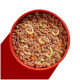 Schüssel mit Haustierfutter, die gemahlenes Fleisch mit buntem Gemüse und Pastaformen zeigt, vor einem leuchtend roten Hintergrund.