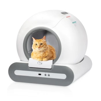 Eine flauschige orange Katze sitzt in einem modernen, weißen Katzenhaus mit abgerundeter Form und grauem Boden, das eine kleine Schublade und Steuerknöpfe hat.