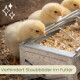 Drei gelbe Küken picken an einem Metallfutterspender mit Mischfutter; Glitzersymbol und Text 'Verhindert Staubbäder im Futter'.