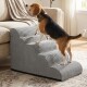 Beagle steigt graue Stoff-Haustiertreppe neben einem beigen Sofa in einem sonnendurchfluteten Wohnzimmer hinauf.