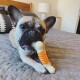 Ein verspielter Französischer Bulldogge, die auf einem grauen, gesteppten Bettlaken liegt und auf einem Gummispielzeug mit orangefarbenem Spiraldesign kaut.