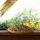 Holzschale mit gemischtem Vogelfutter auf einem Holzgeländer, gelbe Blumen im Hintergrund, goldenes Band mit der Aufschrift „PREMIUM“.