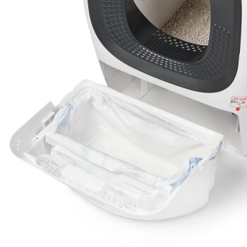 Offene weiße automatische Katzentoilette mit schwarzem Eingang und herausnehmbarem Abfallbehälter, ausgekleidet mit Plastiktüte.