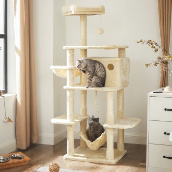 Zwei graue getigerte Katzen spielen auf einem hohen beigen Katzenbaum mit mehreren Ebenen, Hängematten und einem baumelnden Spielzeugball in einem hellen Raum.