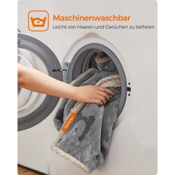 Eine Person fügt eine graue Haustierdecke mit einer cremefarbenen Kante in eine Waschmaschine ein, die als maschinenwaschbar und leicht zu reinigen gekennzeichnet ist.