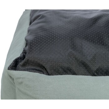 Nahaufnahme eines Haustierbettes mit einem weichen, hellgrünen Außenmaterial und einer strukturierten schwarzen Schlafoberfläche mit kleinen erhöhten Punkten.