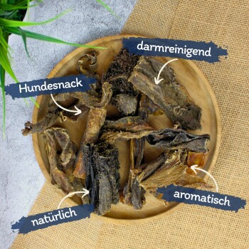 Ein Holzbrett hält verschiedene Hundesnacks, beschriftet auf Deutsch mit 'Hundesnack', 'darmreinigend', 'natürlich' und 'aromatisch'.