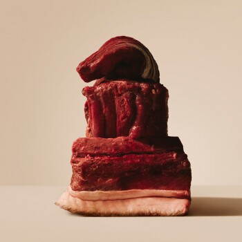 Tranches empilées de viande rouge crue avec couches de graisse visibles, agencement sculptural sur fond beige