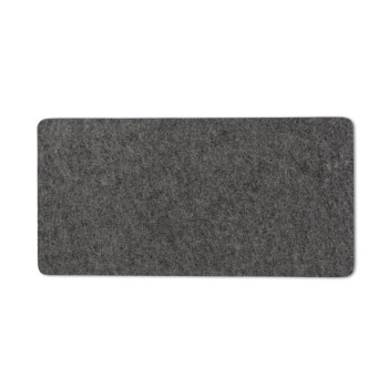 Eine graue getigerte Katze entspannt sich auf einer weichen Matte auf einem weißen Schrank, umgeben von Dekor und gerahmten Bildern. Text: "Gemütlicher Lieblingsplatz."