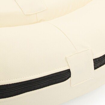 Nahaufnahme eines cremefarbenen Haustierbettes mit einem schwarzen Reißverschluss und genähten Nähten, mit einer weichen, gepolsterten Oberfläche.