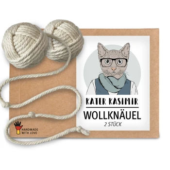 Eine Kraftpapierverpackung mit einer Cartoon-Illustration einer Katze, beschriftet mit 'KATER KASIMIR WOLLKNAÜEL 2 STÜCK,' mit zwei Wollknäueln daneben.