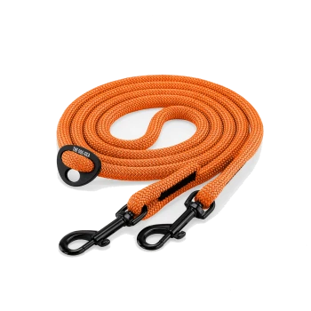 Orange geflochtene Hundeleine aufgerollt mit zwei schwarzen Metallwirbelkarabinern und einem schwarzen Ring mit der Aufschrift 'THE DOG IDEA'.