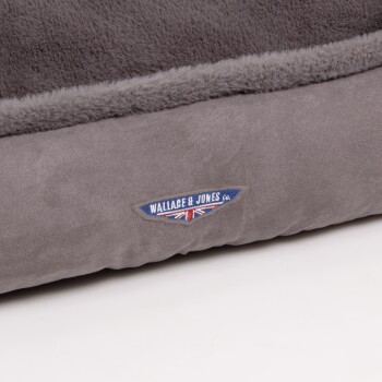 Graues Haustierbett mit einer weichen, plüschigen Oberfläche und einem Etikett mit der Aufschrift "WALLACE & JONES co." mit einem Union Jack Design.