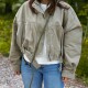Person in beige Jacke und Jeans trägt eine grün geflochtene Hundeleine diagonal über dem Oberkörper.