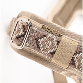 Nahaufnahme eines stilvollen beigen Hundegeschirrs mit einem gemusterten Riemen in Erdtönen und einer Metallschnalle, beschriftet mit "THEDOGIDEA."