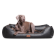 Ein brauner Hund, der auf einem stilvollen schwarzen Hundebett mit gestepptem Design und braunen Akzenten entspannt, mit einem Holzschild, auf dem "tierlindo" steht.