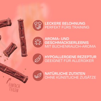 Eine Frau hält eine rosa Tüte Vegdog Beevys Hundeleckerlis, während ein Hund aufmerksam zu ihr aufblickt. Die Tüte zeigt ein Kuh-Logo und Text auf Deutsch.