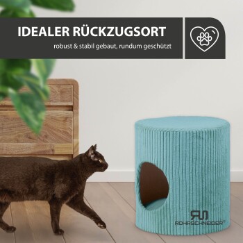 Eine schwarze Katze läuft an einem hellblauen, runden Haustierversteck mit seitlichem Eingang vorbei, mit dem Text 'IDEALER RÜCKZUGSORT' darüber.
