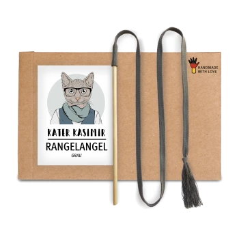 Ein Kartonpaket mit einer Cartoon-Katze in Brille und Schal, beschriftet mit "KATER KASIMIR RANGELANGEL GRAU," mit einem Holzstock und grauem Quastenschnur.