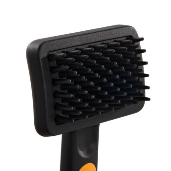 Schwarze Gummibürste für Haustiere mit rechteckigem Kopf aus kurzen flexiblen Borsten und schwarzem Griff mit orangefarbenem Akzent.