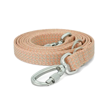 Eine aufgerollte Haustierleine aus weichem rosa und beigem gewebtem Stoff, mit einem stabilen silbernen Metallclip zur Befestigung.