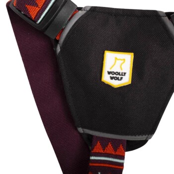 Schwarzes Hundegeschirr mit einem gelben 'Woolly Wolf'-Logo, mit bunten gemusterten Riemen und verstellbarem Schnallenverschluss.