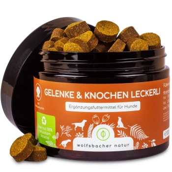 Ein schwarzes Glas mit braunen Hundeleckerlis, beschriftet mit "Gelenke & Knochen Leckerli" von Wolfsbacher Natur, gekennzeichnet als 100% natürlich mit einem Recycling-Symbol.