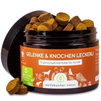Ein schwarzes Glas mit braunen Hundeleckerlis, beschriftet mit "Gelenke & Knochen Leckerli" von Wolfsbacher Natur, gekennzeichnet als 100% natürlich mit einem Recycling-Symbol.