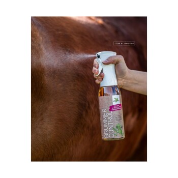 Eine Person sprüht eine Flasche mit der Aufschrift "BRUMMER CONTROL" auf das Fell eines Pferdes und zeigt ein natürliches Insektenschutzmittel für Pferde.