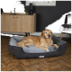 Ein Golden Retriever ruht bequem auf einem plüschigen, grauen und dunkelgrauen Hundebett mit der Aufschrift "Scruffs", in einem modernen Wohnzimmer.