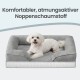 Kleiner weißer Hund auf grauem Bolster-Hundebett; Text lautet 'Komfortabler, atmungsaktiver Noppenschaumstoff'.