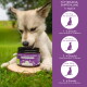 Eine Dose "Ruhe & Relax Leckerli" Hundesnacks auf einem Holzscheit im Gras, mit Dosierungsanweisungen für Hundewicht auf der rechten Seite.