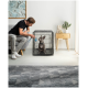 Zwei Hunde, ein brauner Chihuahua und ein tanfarbener Mischling, sitzen in einer schwarzen Draht-Hundekiste in einem gemütlichen Raum mit einer Lampe und Pflanzen.