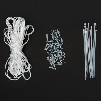 Ein Bündel weißes Seil, eine Sammlung von Metallhaken und -verschlüssen sowie mehrere klare Kunststoff-Zip-Ties auf einem schwarzen Hintergrund angeordnet.