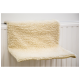 Une étagère pour animaux douce, de couleur crème, avec une texture duveteuse, conçue pour que les chats ou les petits animaux puissent s'y reposer, fixée contre un mur blanc.